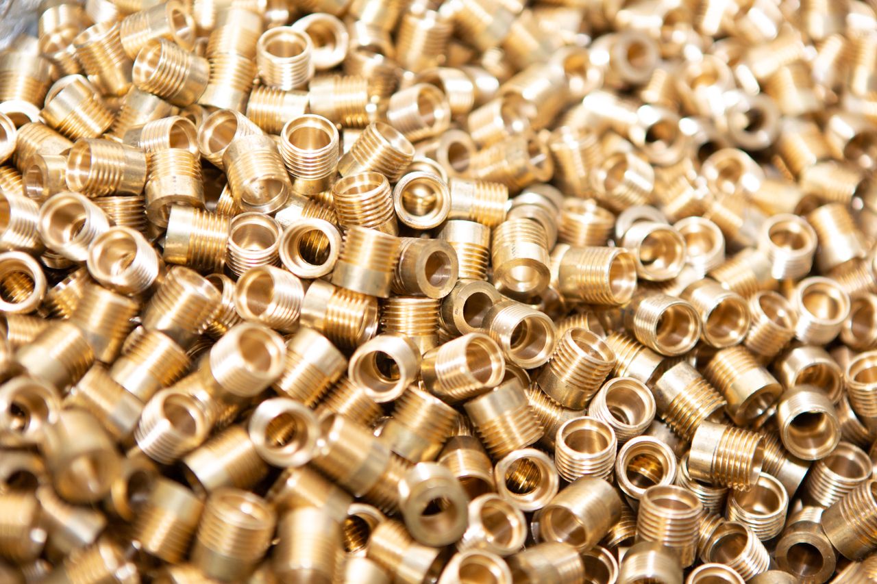 Mastering the First Impression: Your intriguing post title goes here A detailed close-up of a pile of brass screws and nuts with a golden metallic finish.